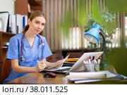 Young woman doctor filling up medical forms on laptop in office. Стоковое фото, фотограф Яков Филимонов / Фотобанк Лори