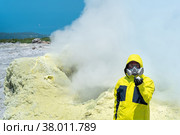 Man volcano scientist on the slope of a volcano among the vapors of a fumarole with sample of a mineral in his hand. Стоковое фото, фотограф Евгений Харитонов / Фотобанк Лори