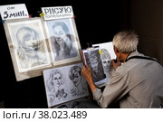 Уличный художник рисует портрет мальчика на пешеходной улице Арбат в центре города Москвы, Россия (2022 год). Редакционное фото, фотограф Николай Винокуров / Фотобанк Лори