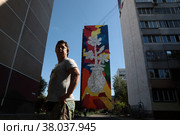 Художник из Москвы Тимур Сафаров у своего мурала, микрорайон Железнодорожный (2022 год). Редакционное фото, фотограф Дмитрий Неумоин / Фотобанк Лори