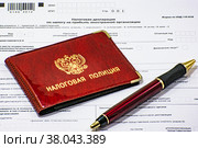 Авторучка и удостоверение налоговой полиции на бланке налоговой декларации по налогу на прибыль иностранной организации (2022 год). Редакционное фото, фотограф Анна Аникова / Фотобанк Лори