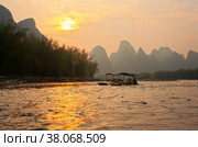 China. Yangshuo. Xingping. Li (Lijiang) River with green karst hills. Tourists come on traditional bamboo rafts to the river bank to watch the sunset. Natural background (2011 год). Стоковое фото, фотограф Виктория Катьянова / Фотобанк Лори