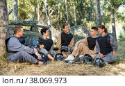 Positive paintball players sitting on battleground and chatting. Стоковое фото, фотограф Яков Филимонов / Фотобанк Лори