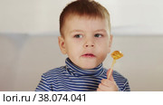 The boy eats a candy in the form of a cockerel. Стоковое видео, видеограф Потийко Сергей / Фотобанк Лори