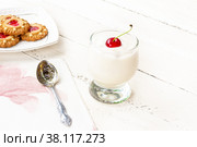 Milk yogurt with cherries in a glass and cookies with hearts on a saucer on a white wooden table close-up. Стоковое фото, фотограф Андрей С / Фотобанк Лори