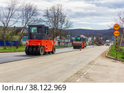 Kamennomostsky, Russia - April 13, 2019: rollers for asphalt rolling out new asphalt on the highway in the village. Редакционное фото, фотограф Андрей С / Фотобанк Лори