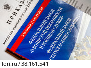 Книжка с Федеральными законами о военной службе и приказ Министра обороны РФ лежат на столе (2022 год). Редакционное фото, фотограф Николай Винокуров / Фотобанк Лори