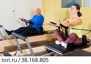 Woman pulling stretch band sitting on pilates training machin. Стоковое фото, фотограф Яков Филимонов / Фотобанк Лори