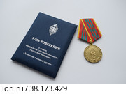 Удостоверение и медаль ФСБ РФ "За отличие в военной службе" на светлом фоне (2022 год). Редакционное фото, фотограф Наталья Зверева / Фотобанк Лори