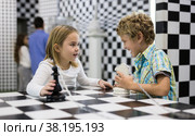 Boy adn girl solving puzzle together in room stylized like chessboard. Стоковое фото, фотограф Яков Филимонов / Фотобанк Лори