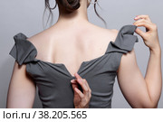 Woman unzips the zipper on the dress. Bunette female rear view with hair knot and earrings in the ears. Стоковое фото, фотограф Сергей Пристяжнюк (Serg Zastavkin) / Фотобанк Лори