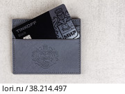Adygea, Russia - October 12, 2022: credit card tinkoff black world in a card holder on a gray background with copy space. Редакционное фото, фотограф Андрей С / Фотобанк Лори