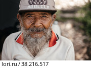 Portrait of an old Balinese man in an old sweater and cap. Indonesia, Bali, September 27, 2022. Редакционное фото, фотограф Евдокимов Максим / Фотобанк Лори