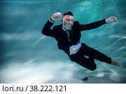 Cute successful young businessman with his mouth taped underwater. Drowning is elimination of competitor in pond. Concept of business competition, rivalry, and unwanted partnerships. Copy space. Стоковое фото, фотограф Aleksandr Golubev / Фотобанк Лори