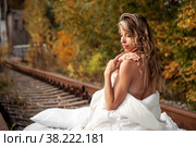 Young emotional pretty woman in her bed on railway tracks. Single female dreams in nature. Concept of problem of travel ban and inability to move. Stay at home. Copying space for site. Стоковое фото, фотограф Aleksandr Golubev / Фотобанк Лори