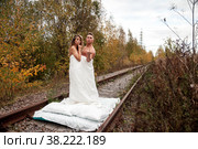 Young cute couple on their honeymoon woman and man embrace in their bed on railway tracks. Concept of romantic travel ban and inability to move. Stay at home. Copying space for a site. Стоковое фото, фотограф Aleksandr Golubev / Фотобанк Лори