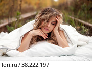Young emotional pretty woman in her bed on railway tracks. Single female dreams in nature. Concept of problem of travel ban and inability to move. Stay at home. Copying space for site. Стоковое фото, фотограф Aleksandr Golubev / Фотобанк Лори