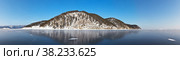 Frozen Baikal Lake in winter season. Panoramic view on coast near Bolshoye Goloustnoye village. Snow-capped hills are reflected in the blue clear ice. Beautiful winter landscape. Natural cold background. Стоковое фото, фотограф Виктория Катьянова / Фотобанк Лори