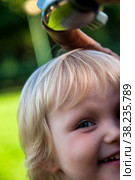 Cute little blond baby girl two year old playing with teddy bear on fresh green grass with flowers. Kid having fun making first steps on mowed natural lawn. Happy and healthy childhood concept. Стоковое фото, фотограф Aleksandr Golubev / Фотобанк Лори