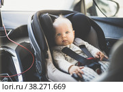Cute little baby boy strapped into infant car seat in passenger compartment during car drive. Стоковое фото, фотограф Matej Kastelic / Фотобанк Лори