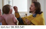RUSSIA, KAZAN 08-28-2022: Orthodox priest drips oil on a baptized crying baby. Редакционное видео, видеограф Константин Шишкин / Фотобанк Лори