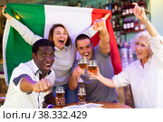 Cheerful diverse soccer supporters holding the flag of Mexico and enjoing beer in the sport bar. Стоковое фото, фотограф Яков Филимонов / Фотобанк Лори