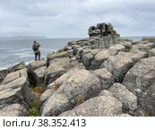 Турист фотографирует море с побережья полуострова Брюса осенью в дождливую погоду. Россия, Приморский край (2022 год). Редакционное фото, фотограф Овчинникова Ирина / Фотобанк Лори
