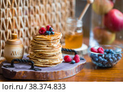 Delicious pancakes with honey, blueberries and raspberries. Next to it is a wooden barrel with an inscription in Russian: "honey". The concept of the Maslenitsa holiday. Стоковое фото, фотограф Photojuli / Фотобанк Лори