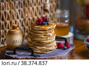 Delicious pancakes with honey, blueberries and raspberries. Next to it is a wooden barrel with an inscription in Russian: "honey". The concept of the Maslenitsa holiday. Стоковое фото, фотограф Photojuli / Фотобанк Лори
