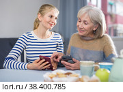 Mature woman with her adult daughter looking at photos on a mobile phone. Стоковое фото, фотограф Яков Филимонов / Фотобанк Лори