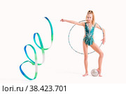 Smiling girl professional gymnast in an emerald swimsuit poses with ribbon, hoop and ball isolated on white background. Стоковое фото, фотограф Мария Мороз / Фотобанк Лори