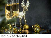 С Новым 2023 годом. Фон рождественских и новогодних праздников с пространством для копирования. Два бокала и золотой блестящий олень на темном фоне. Стоковое фото, фотограф Photojuli / Фотобанк Лори