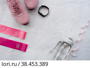 Здоровый образ жизни и фитнес. Спорт. Утренняя пробежка и занятия. Кроссовки, фитнес-резинки, умный фитнес-трекер, беспроводные наушники и бутылка воды на сером фоне. Вид сверху и плоское расположение. Стоковое фото, фотограф Photojuli / Фотобанк Лори