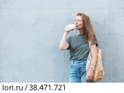 Современная стильная женщина со стеклянной бутылкой молока и авоськой купила хлеб. Девушка на фоне серой стены. Концепция здорового питания и экологии. Отказ от пластиковых пакетов. Стоковое фото, фотограф Photojuli / Фотобанк Лори