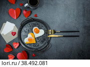 Homemade fried egg in a vintage pan, mug of coffee,hearts and stylish cutlery on a dark background. Eggs in the shape of a heart. View from above. Copy space for text. Flatly. Стоковое фото, фотограф Photojuli / Фотобанк Лори