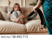 Mother wants to punish her child daughter with belt in hand. Angry mom punishes teen girl for offense and hits baby with belt. Concept of family quarrels, problems and parenting. Copy text space. Стоковое фото, фотограф Aleksandr Golubev / Фотобанк Лори