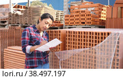 Female worker checking quantity of red bricks in warehouse of building materials. Стоковое видео, видеограф Яков Филимонов / Фотобанк Лори
