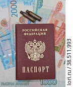 Российский паспорт и гильзы от патронов лежат на фоне из рублевых купюр. Стоковое фото, фотограф Цибаев Алексей / Фотобанк Лори