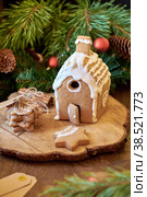 Gingerbread House and Gingerbread. Wooden background with pine branches. New Year. Christmas. Rustic. Side view. Стоковое фото, фотограф Лютик Фалисова / Фотобанк Лори
