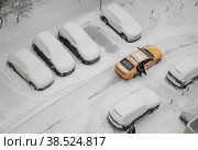Зима, январский день, глубокий снег. Мужчина садится в яркое желтое яндекс-такси, припаркованное во дворе дома между полностью засыпанными снегом машинами (2022 год). Редакционное фото, фотограф Наталья Николаева / Фотобанк Лори