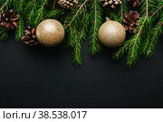 Новогодний фон с еловыми ветками и золотыми елочными шарами, на черном деревянном фоне. Новый год и рождество. Место для текста. Вид сверху. Фон и текстуры. Стоковое фото, фотограф Андрей Пустякин / Фотобанк Лори