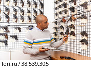 Latin american man examining sporting revolver in gun store. Стоковое фото, фотограф Яков Филимонов / Фотобанк Лори