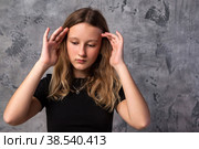 Face sorrowful sad teen girl in black clothes thinking looking down, at grey background. Pensive thoughtful teenager girl 12 years old posing in studio. Kid emotion concept. Copy text space. Стоковое фото, фотограф Aleksandr Golubev / Фотобанк Лори