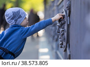 Россия. Санкт-Петербург. Виды Летнего сада. Ребенок рассматривает забор с барельефом изображения Медузы Горгоны. Russia. Saint-Petersburg. Types of Summer Garden. A child examines a fence with a bas-relief image of a Gorgon Medusa. (2021 год). Стоковое фото, фотограф Алексей Смышляев / Фотобанк Лори