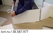 The man connects the side panel and the cover with a Euro screw. Wooden modular rack. Assembling a modular rack. Overall plan. Стоковое видео, видеограф Vadzim Yakubovich / Фотобанк Лори