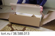 Unpacking the modular rack. The man opens the package and examines the wooden elements. Overall plan. Стоковое видео, видеограф Vadzim Yakubovich / Фотобанк Лори