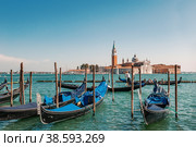 VENICE, ITALY-SEPTEMBER 4, 2018 Venetian gondolier punting gondola through grand canal waters - View of San Giorgio Island in Venice with wooden buoys in Giudecca Canal. Редакционное фото, фотограф Оксана Медведева / Фотобанк Лори