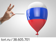 Кто-то пытается проткнуть надувной шар стилизованный в цвета Российского флага. Внешние угрозы. Геополитическая тематика. Стоковое фото, фотограф Happyphotons / Фотобанк Лори