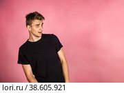 Dissatisfied young man looking unpleasantly away, expresses aversion, smirking at pink background. Guy in black t-shirt scared, negative face expressions concept. Advertising. Copy text space. Стоковое фото, фотограф Aleksandr Golubev / Фотобанк Лори