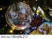 Крупным планом елочная игрушка с портретом первого космонавта Юрия Гагарина на уличной новогодней елке в центре города Москвы в дни новогодних праздников, Россия (2023 год). Редакционное фото, фотограф Николай Винокуров / Фотобанк Лори